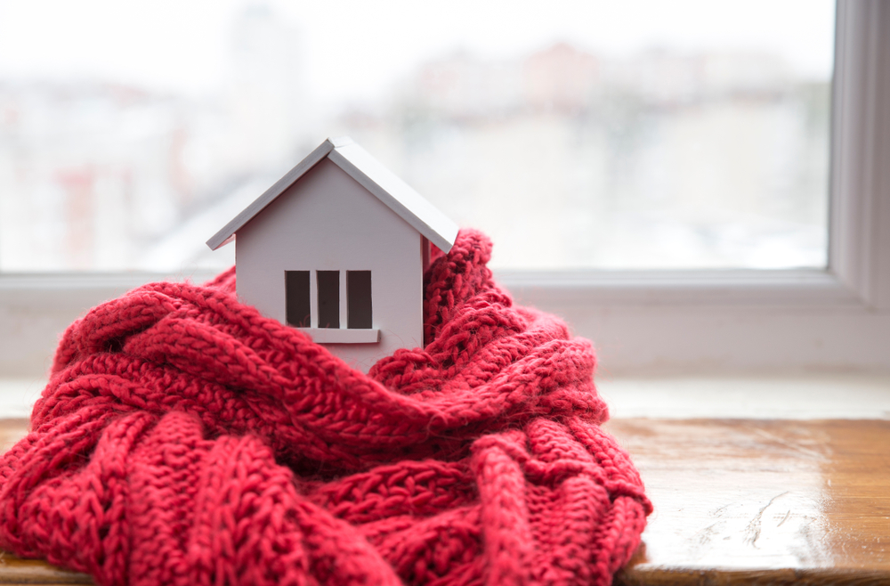 Heating concept - miniature model house wrapped in a red blanket