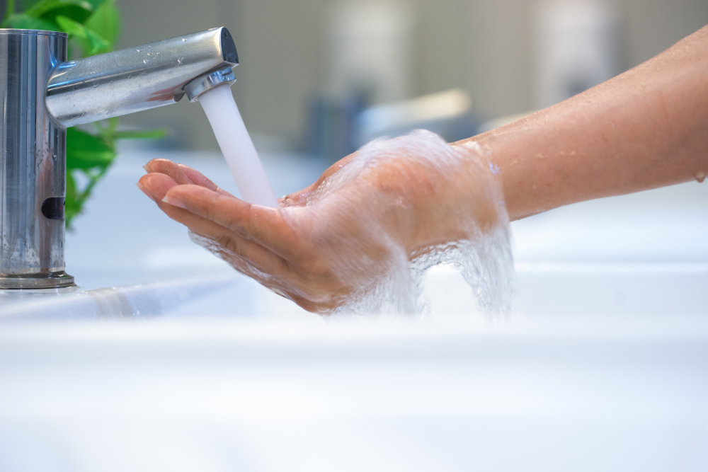 Washing soapy hand under flowing bathroom tap