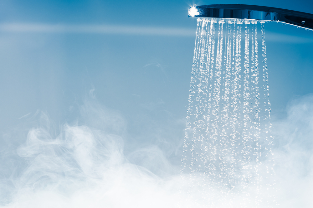 Hot water flowing from a shower head, steam gathering