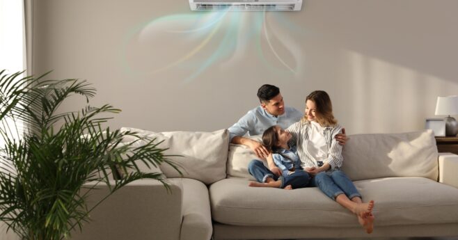 Family resting on a cream modular couch as the split system above them blows out cool air.